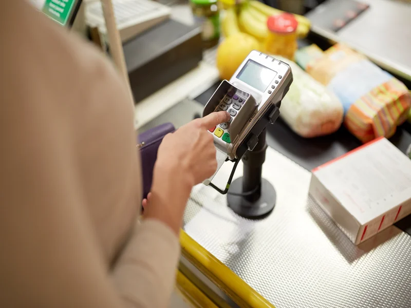 Woman entering PIN code at store cash register